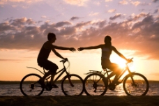 夕阳下海边骑自行车的情侣图片