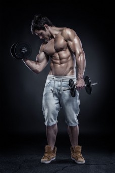 用哑铃展示肌肉的男人图片