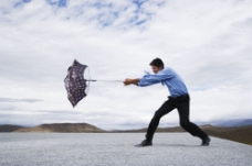 拿伞的男人与风对抗图片